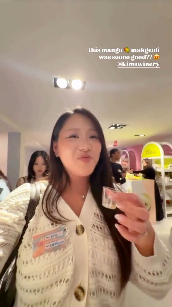 A woman tasting Kim's Makgeolli Mango and loving it,