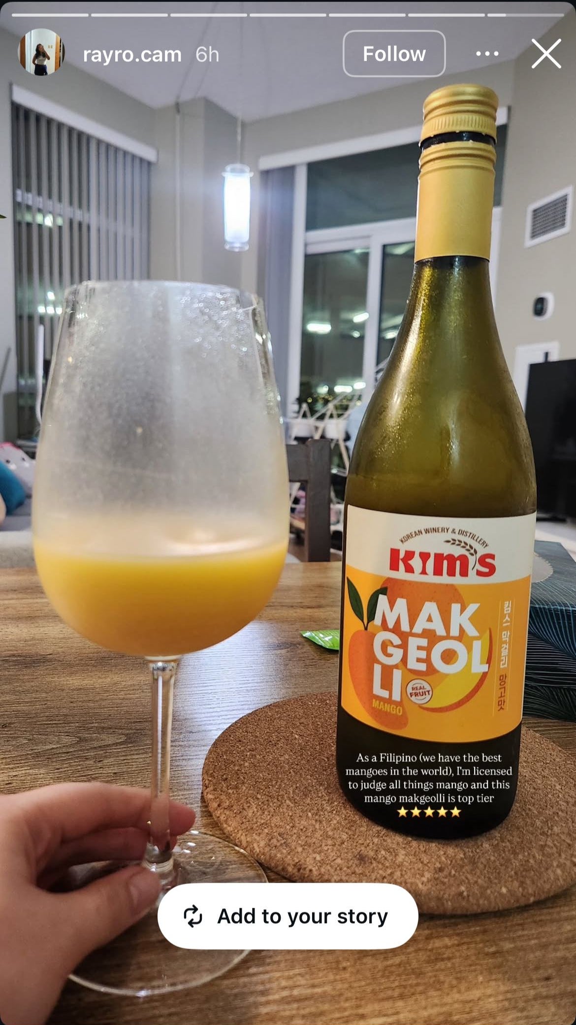 Bottle of Kim's Makgeolli Mango with a wine glass of creamy orange coloured mango makgeolli poured in it with a 5 star rating.