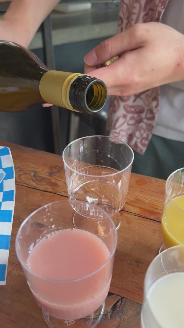 Kim’s Makgeolli Moju being poured into a wine glass, showing smooth golden brown rice wine.
