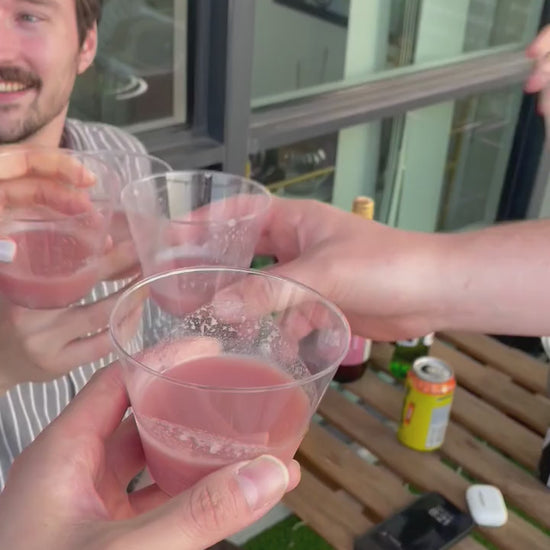 Group of friends raising glasses of Kim’s Makgeolli for a cheers at an outdoor patio table.