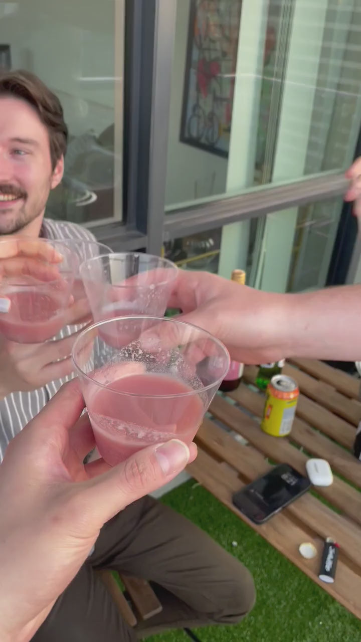 Group of friends raising glasses of Kim’s Makgeolli for a cheers at an outdoor patio table.